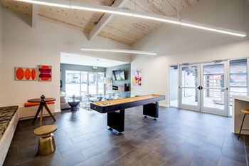A modern office space with a long table and chairs, a bench, and a tripod on the left side.